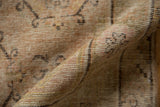 Textured roll of a distressed Khotan rug revealing the hand-knotted foundation and soft, faded tones.