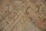 Distressed vintage Khotan rug corner: textured pile, faded patterns, visible woven back.