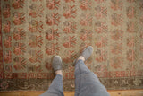 Worn vintage Khotan rug, showing faded beige field, pale orange plant motifs, and border.