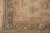 Distressed vintage Khotan rug corner, with faded beige, pale orange plant motifs and fringe.