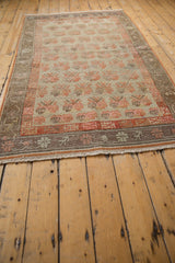 Distressed Khotan rug texture with muted beige and pale burnt orange motif.