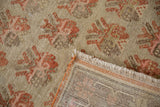 Distressed Khotan rug close-up revealing germinating plant pattern, low pile, and hand-knotted foundation.