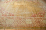 Vintage Oushak rug corner showing gold and terra cotta floral border and worn pile.