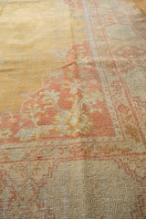 Oushak rug corner with pale terra cotta floral spandrels, visible knot heads.