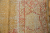 Vintage Oushak rug with aged gold and ivory fields, revealing knot heads and terra cotta motifs.