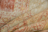 Curled vintage Oushak rug detail showing variegated gold, ivory, and terra cotta texture.