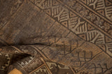 Folded vintage Belouch rug showing finned plant motifs, brown hues, and low pile.