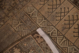 Folded vintage Belouch rug showing side selvage and compartmentalized geometric patterns.