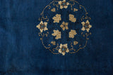 Delicate vinery and floral motifs forming a roundel on this indigo Peking rug.