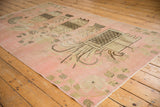 Distressed pink vintage Khotan rug with pictorial vase motif in beige and brown.