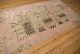 Vintage Khotan rug displaying pictorial vase, checkered base, and worn pink field.