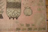 Distressed Khotan rug fragment showing pink field with pictorial vases and leaf motifs.