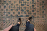 Distressed Khotan carpet with soft teal and pale mauve geometric panel design.