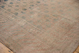 Distressed vintage Khotan carpet corner with even wear, faded dusty teal, pale mauve geometric pattern.