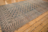 Distressed Khotan carpet showing even wear, soft panel motifs in muted teal, ivory, and mauve.