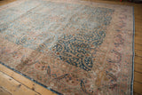 Curvilinear leaf border with blush and beige tones on a distressed vintage Meshed rug, showing wear.