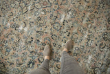 Vintage distressed Arak carpet with faded floral patterns in blush, ivory, and soft blue.