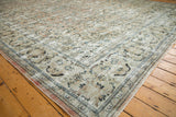 Distressed vintage Arak carpet corner, with floral patterns in ivory, navy, and soft blush.