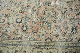 Distressed floral field transitioning to a patterned navy and ivory border on the Arak rug.