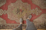 Distressed Oushak rug showing central floral medallion, Rococo leaves, and muted tones.