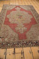 Vintage distressed Oushak rug corner showing decorative border and germinating plant motif.