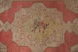 Distressed Rococo leaves and central floral motif, with faded blush and beige tones on Oushak pile.