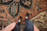 Antique Serapi carpet's geometric floral cross-sections in pale terra cotta, navy, mallard green.