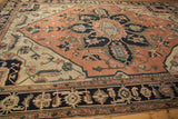 Bold navy geometric border of antique Serapi rug, with pale terra cotta field and vinery.