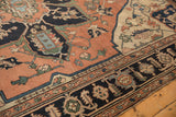 Corner of Antique Serapi carpet showing pale terra cotta field, navy border, and abrash-rich floral vinery.