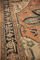 Detail of Antique Serapi carpet: navy geometric border and terra cotta field with large floral vinery.