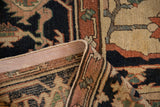 Folded edge of antique Serapi carpet with navy, terra cotta, hand-knotted weave, and intact selvage.