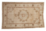 Distressed vintage Oushak rug with roundel pomegranate medallion in ivory and brown tones.