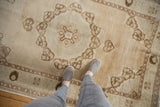 Distressed vintage Oushak rug featuring abrashed field, pomegranate style medallion, and plant motifs.