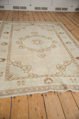 Distressed vintage Oushak rug showing texture, pomegranate medallion, and subtle plant motifs.