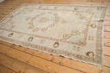 Distressed vintage Oushak rug corner showing worn antique ivory pile and coffee brown motifs.