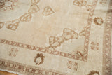 Muted ivory, coffee brown germinating plant motifs on distressed vintage Oushak rug pile.