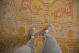 Antique Oushak rug showing pale lemon, gold, blush serrated field and unusual banded border.
