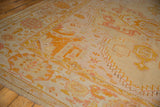 Antique Oushak carpet corner: wide banded border, serrated field motifs, pale lemon, gold, blush.