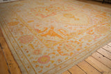 Antique Oushak carpet corner showing wide banded border, serrated motifs, and pale lemon, orange.