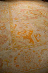 Antique Oushak corner with wide saffron border, pale lemon field, and soft rose motifs.