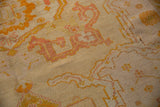 Antique Oushak carpet close-up, pale yellow, orange, and blush serrated design with low pile.