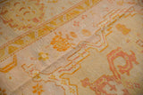 Antique Oushak carpet: splayed floral motifs, serrated contour in pale gold, blush, with even wear.