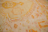 Antique Oushak rug close-up: serrated lightening contour motif in saffron, gold, and blush tones.