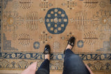 Navy blue roundel medallion and tree-of-life motifs on distressed pale bronze Khotan rug.