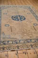 Distressed vintage Khotan rug with worn texture and navy tree of life motifs.