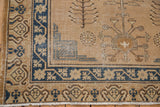 Vintage distressed Khotan rug corner with rich navy and ivory floral border details.