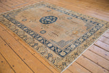 Vintage distressed Khotan rug corner, with navy floral guls and worn ivory fringe.