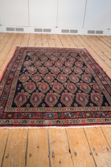Traditional Persian Senneh rug's multi-banded border and navy field with oversized boteh motifs.
