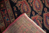 Hand-knotted vintage Senneh rug folded, revealing tight foundation, pink selvage, and navy boteh.