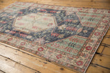 Hand-knotted distressed Turkish Sparta rug corner with pale cherry red floral border, mint green spandrel.